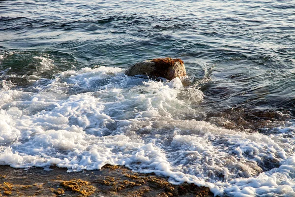 Fala jest przekształcona w pianki na kamienistej plaży. Selektywny fokus — Zdjęcie stockowe