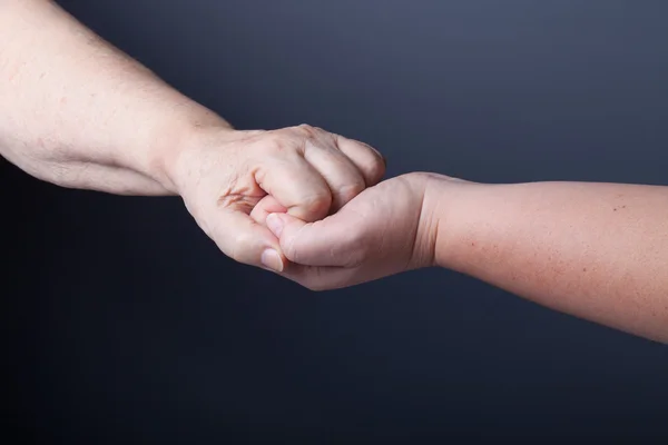 Handen van ouderen en jonge vrouwen op zwarte achtergrond — Stockfoto