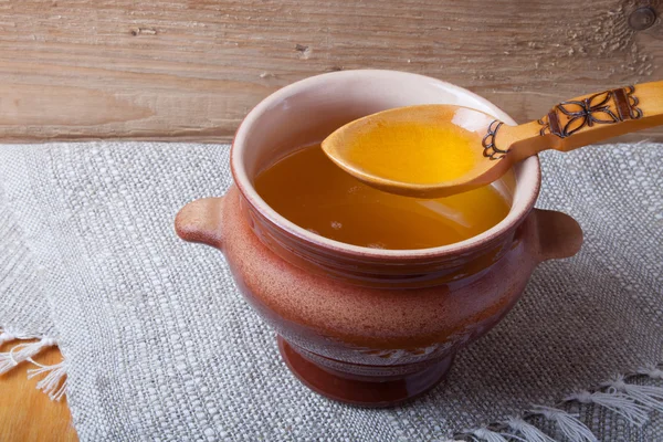 Clay pot with ghee and spoon on linen napkin. Rustic still life. — Stock Photo, Image