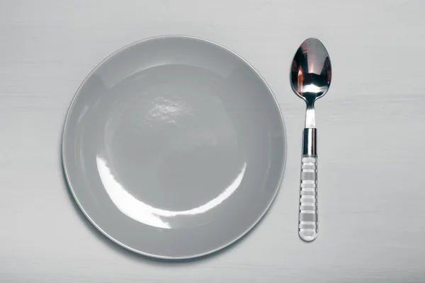 Plate and spoon  on a wooden background. Toned — Stock Photo, Image