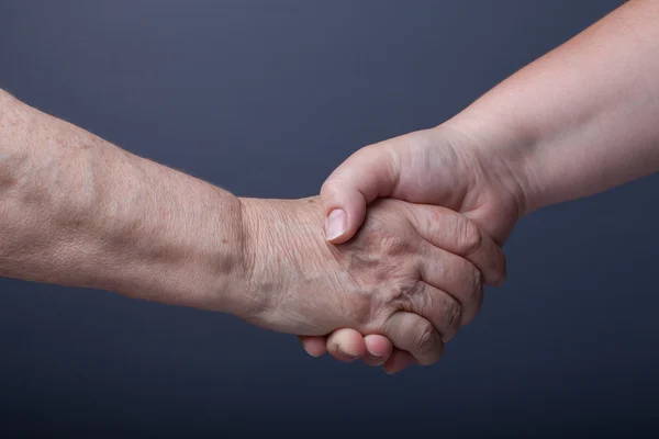 Händerna på äldre och unga kvinnor på svart bakgrund — Stockfoto