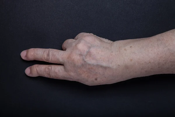黒の背景に高齢者の女性の手 — ストック写真