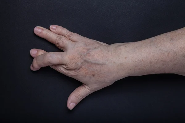 黒の背景に高齢者の女性の手 — ストック写真