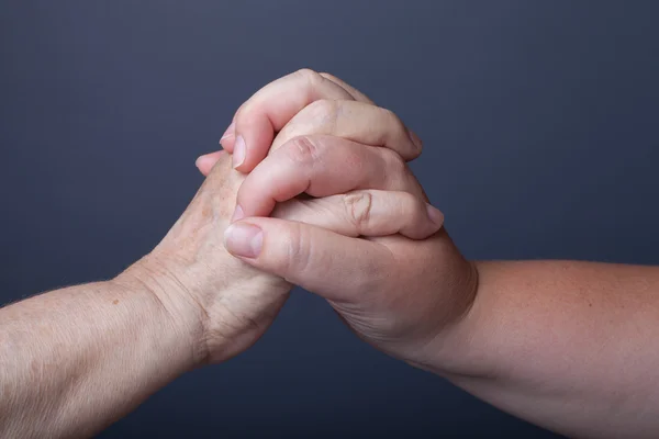Händerna på äldre och unga kvinnor på svart bakgrund — Stockfoto