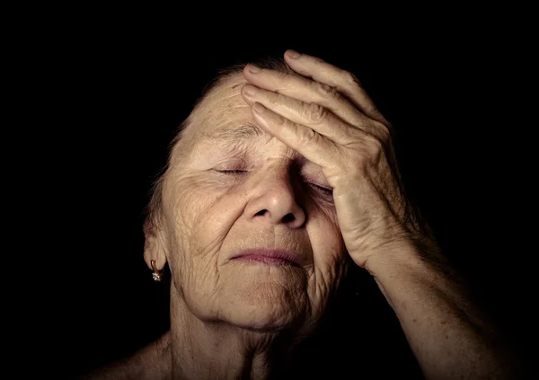 Portrait of elderly woman. Closes eyes with hands. Toned — Stock Photo, Image
