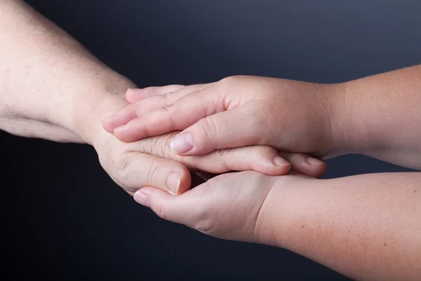 Handen van ouderen en jonge vrouwen op zwarte achtergrond — Stockfoto