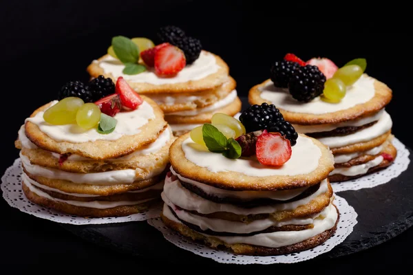 Keks hausgemachte Kuchen mit Sahne und Beeren auf schwarzem Hintergrund — Stockfoto