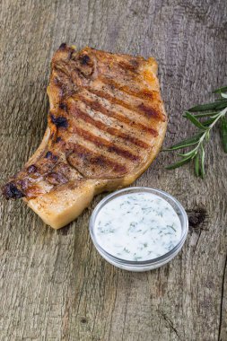 Büyük bir parça taze domuz eti ızgara tepsisinde hazırlanmış ve arka plan için eski ahşap masada ayyaş var..