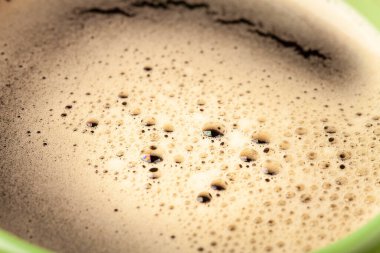 Yeşil fincanda köpük olan sıcak taze kahvenin üst görüntüsü..