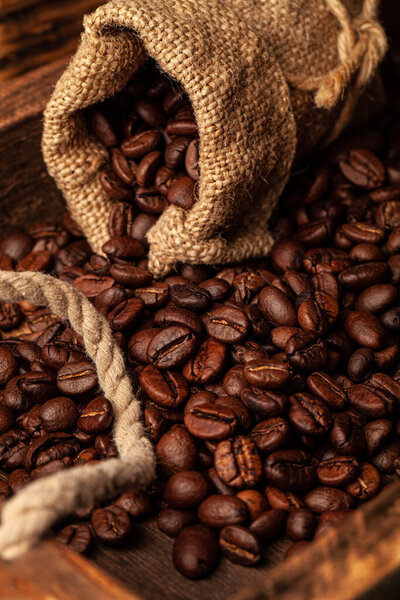Roasted coffee beans on the old dark wooden background for wallpaper or decor.