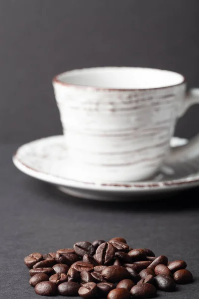 Roasted coffee beans and light cup on the black background. Shallow depth of field. Selected focuse.