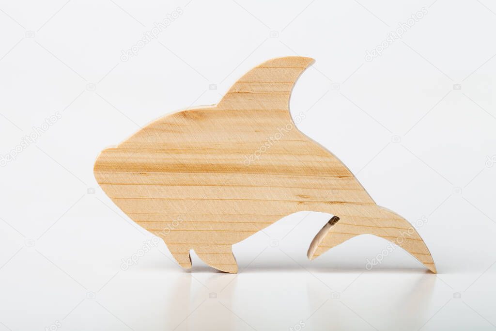 A figurine of a shark or fish, carved from solid pine with a hand jigsaw. On a white background .