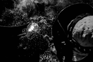 Deneyimli bir kaynakçı. Demir fırınının hazırlık ve kaynak işlemleri. Seçime odaklan. Yüzeyin derinliği. Ayarlanmış.