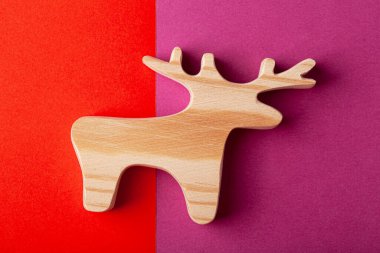 Katı çam ağacından oyulmuş bir geyik ya da geyik heykeli. Çok renkli bir arkaplanda.