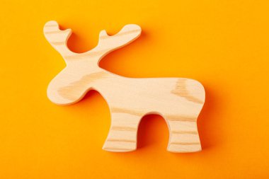 Katı bir çam ağacından oyulmuş bir geyik ya da geyik heykeli. Sarı arka planda.