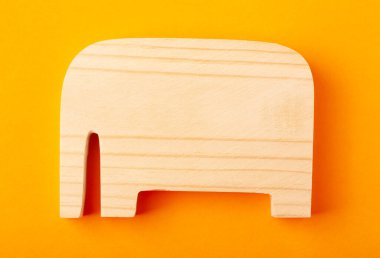 Katı çam ağacından elle oyulmuş fil heykeli. Sarı arka planda.