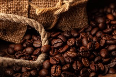 Duvar kağıdı ya da dekor için eski koyu ahşap arka planda kavrulmuş kahve çekirdekleri..