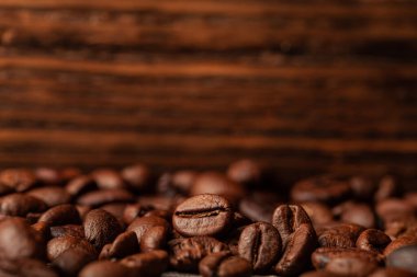 Duvar kağıdı ya da dekor için eski koyu ahşap arka planda kavrulmuş kahve çekirdekleri..