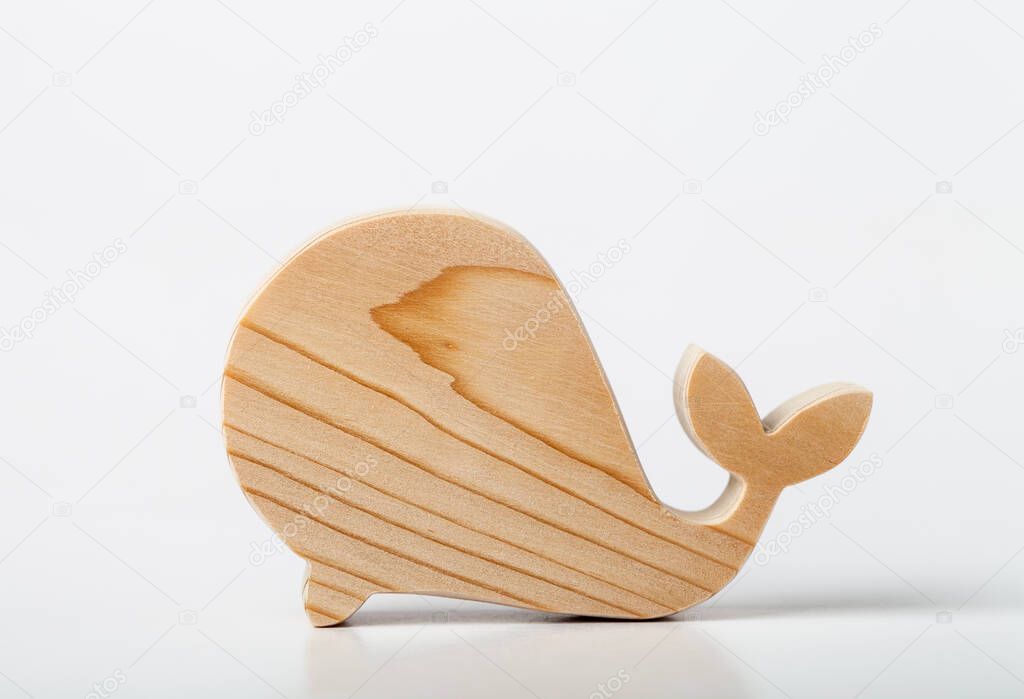 A figurine of a whale carved from solid pine by a hand jigsaw. On a white background .