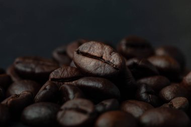 Duvar kağıdı veya dekor için eski koyu ahşap arka planda kavrulmuş kahve çekirdekleri. Yüzeyin derinliği. Seçili odak.