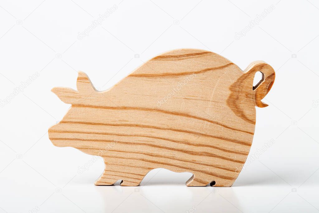 Pig figurine carved from solid pine by hand jigsaw. On a white background .