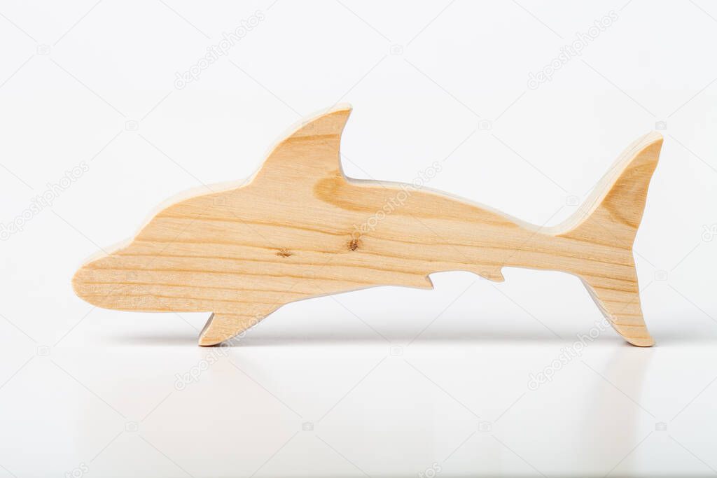 Dolphin figurine carved from solid pine by hand jigsaw. On a white background .
