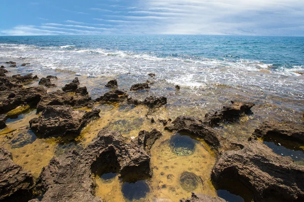 Receding sea coastline and stone with water pits — Stock Photo, Image