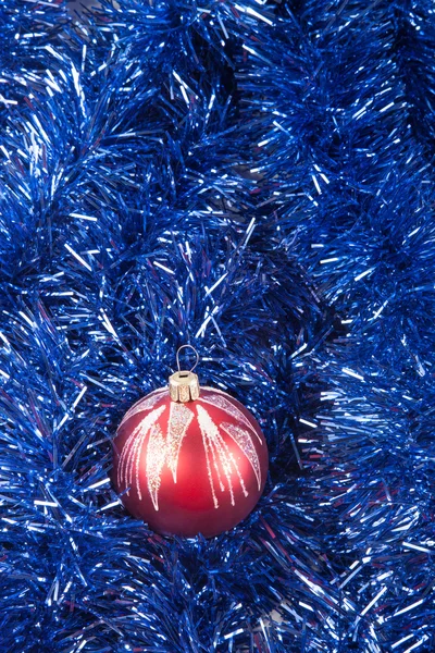 Bola de Natal vermelho no fundo de ouropel azul — Fotografia de Stock