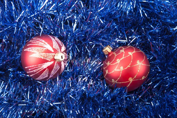 Red Christmas balls on the background of blue tinsel — Stock Photo, Image
