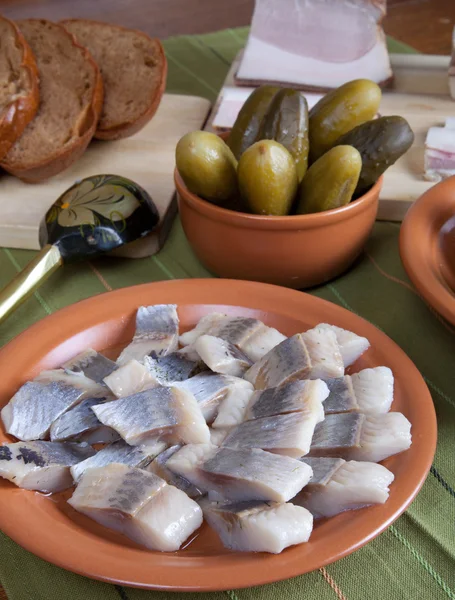 Arenque, pan, pepinillos y tocino con platos en una servilleta verde — Foto de Stock