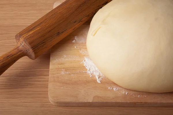 Dough on a board and rolling pin with flour dusting. Close-up — Stock Photo, Image