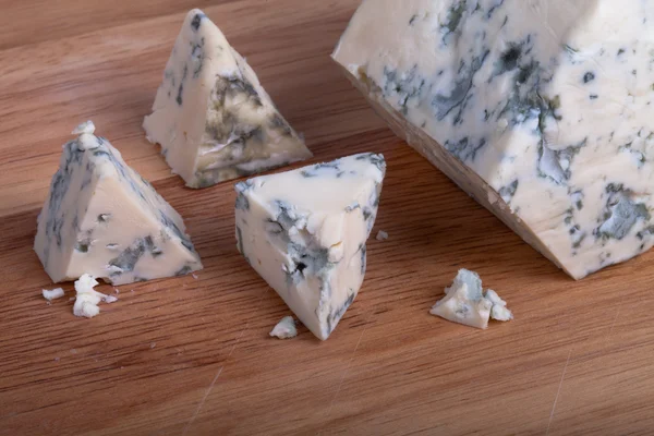 Синий сыр с ломтиками на деревянной доске. Мелкая глубина резкости — стоковое фото