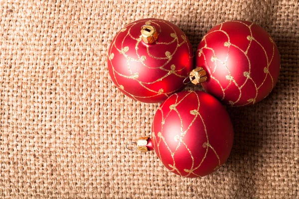 Three red Christmas tree ball on sacking — Stock Photo, Image