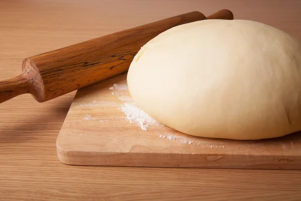 Dough on a board and rolling pin with flour for sprinkling — Stock Photo, Image