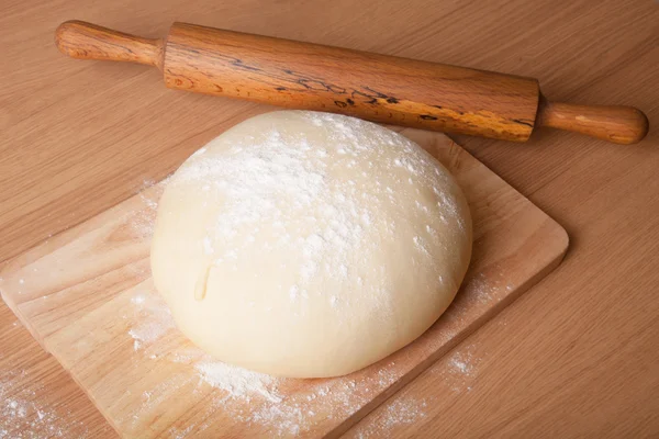 Massa de farinha em uma prancha e rolo com farinha para polvilhar — Fotografia de Stock