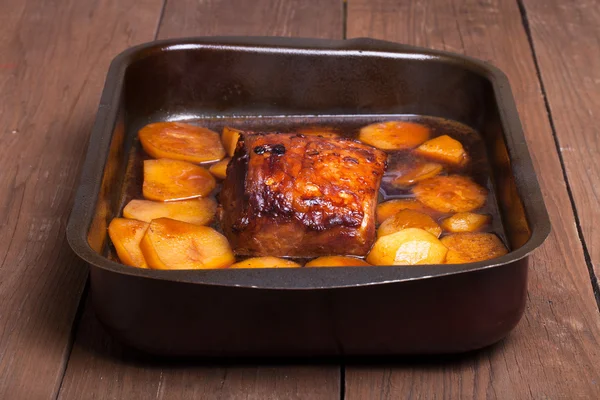 Piece of pork and potatoes in the pan for roasting on an old woo — Stock Photo, Image