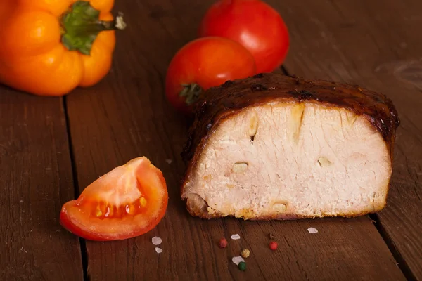 Piece of pork, peppers and tomatoes on an old wooden table — Stock Photo, Image