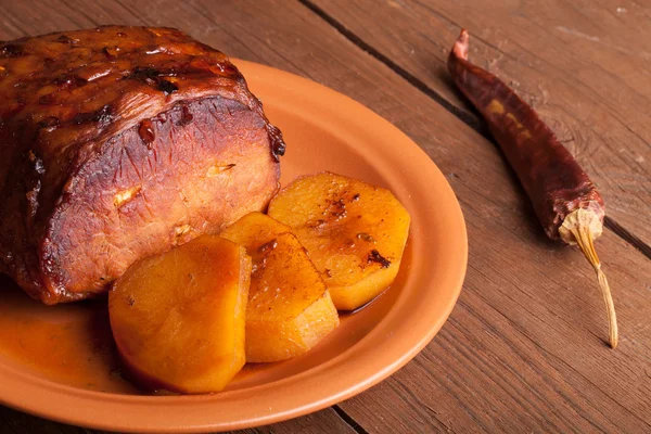 Pezzo di maiale, peperoni e patate in una vecchia tavola di legno — Foto Stock