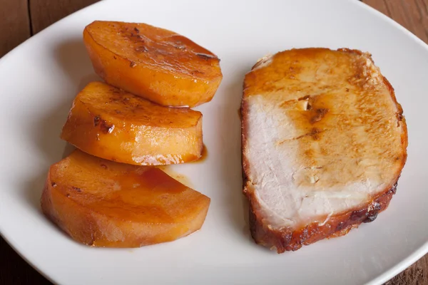 Кусок свинины с картошкой на белой тарелке — стоковое фото