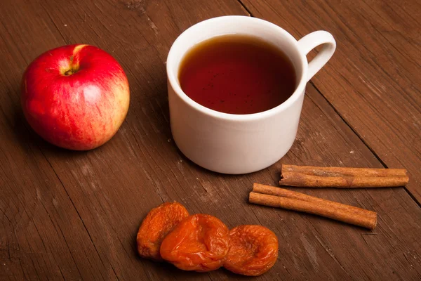 Tasse Tee auf altem Holztisch mit rotem Apfel, getrockneten Aprikosen — Stockfoto