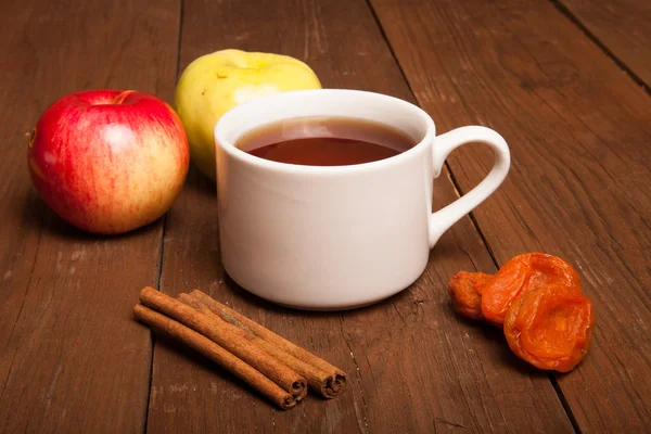 Cup of tea on old wooden table with two apples, dried apricots a — Stock Photo, Image