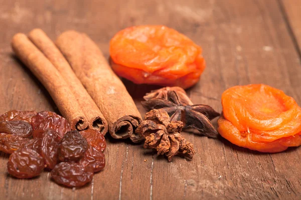 Rozinky, skořice, anýz a sušené meruňky, leží na staré dřevo — Stock fotografie