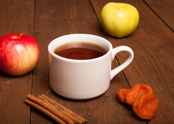 Cup of tea on old wooden table with two apples, dried apricots a — Stock Photo, Image