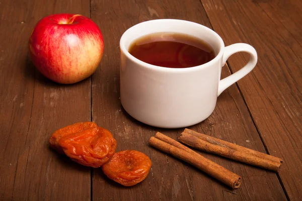 Tazza di tè sul vecchio tavolo di legno con mela, albicocche secche e c — Foto Stock