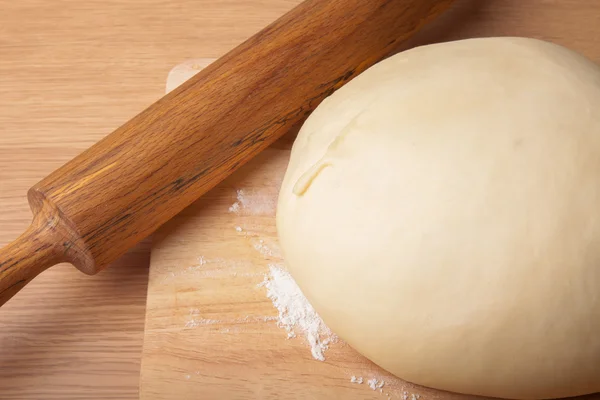 Dough on a board and rolling pin with flour for sprinkling — Stock Photo, Image