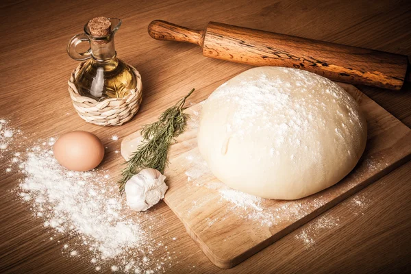 Dough on a board with flour. olive oil, eggs, rolling pin, garli — Stock Photo, Image