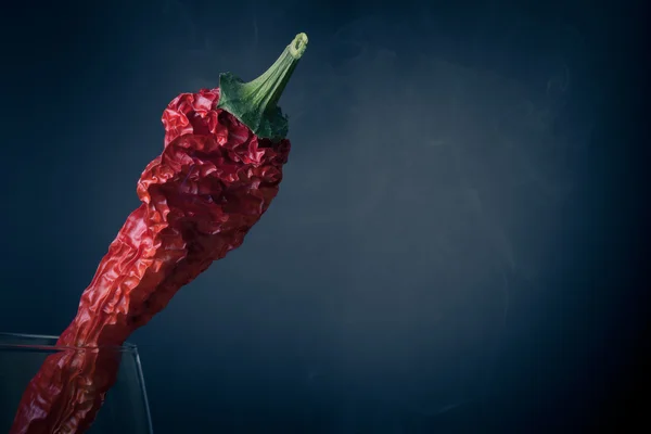 Red hot chili peppers in a glass on a dark background with smoke — Stock Photo, Image