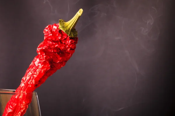 Red hot chili peppers in a glass on a dark background with smoke — Stock Photo, Image