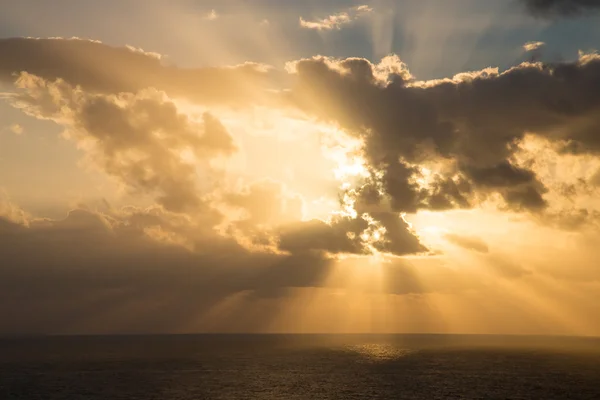 Dramatický západ slunce paprsky přes zataženou tmavou oblohu nad oceánem — Stock fotografie