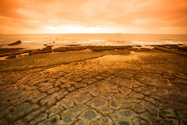 Atlantische kust bij laag tij. gebarsten stenen. Getint. — Stockfoto